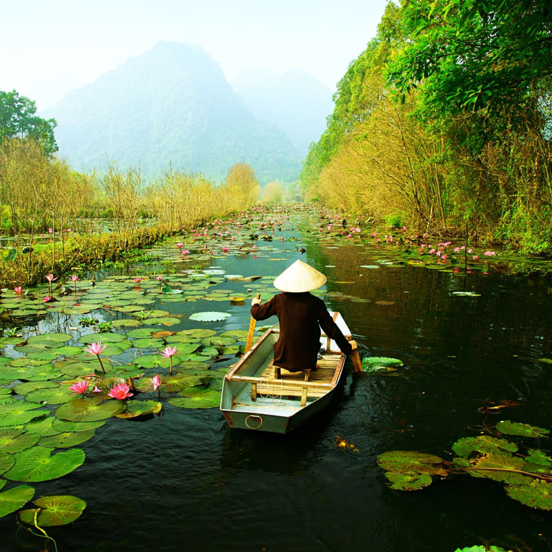 Man on a small boat in a lake in Ninh Binh