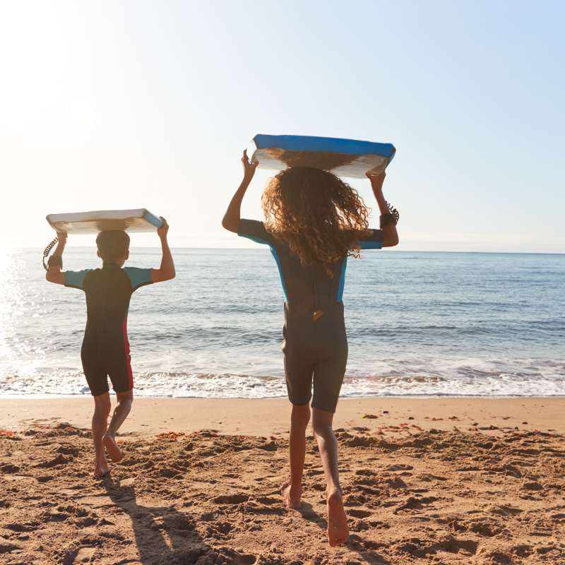 Kids running with body boards on beach